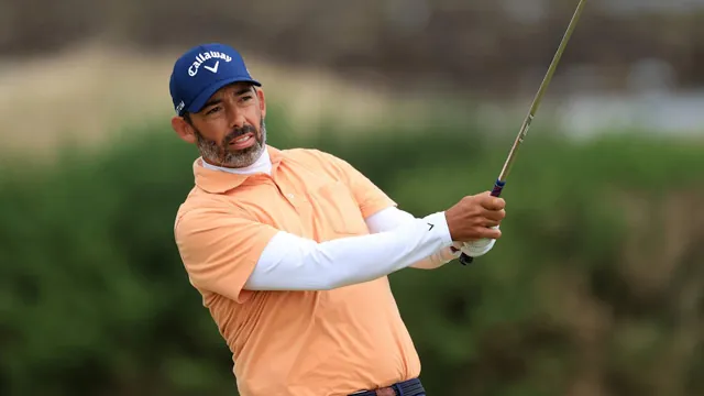 Larrazábal golpeando la bola en un campo de golf, con polo naranja, gorra azul y manga blanca