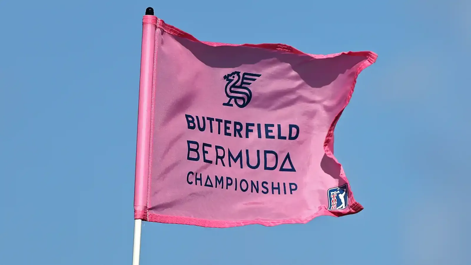 Bandera rosa de golf ondeando contra un cielo azul, con el logo del Butterfield Bermuda Championship del PGA Tour