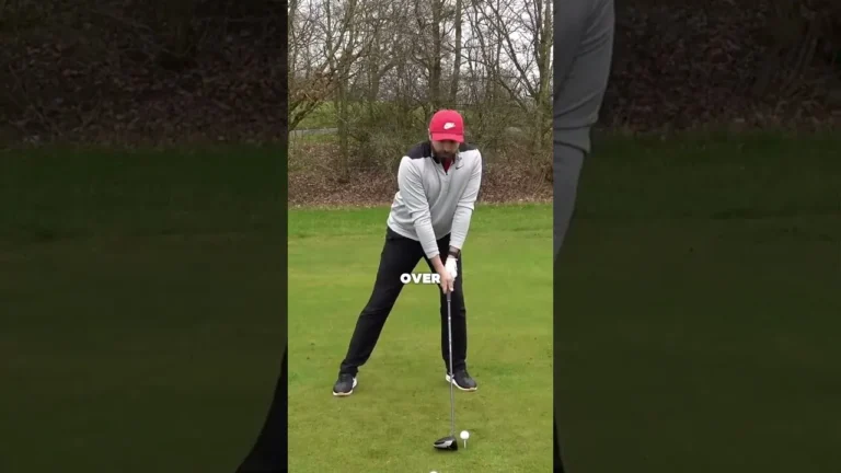 Rick Shiels prepara un golpe con el driver en un campo de golf, con gorra roja y jersey gris