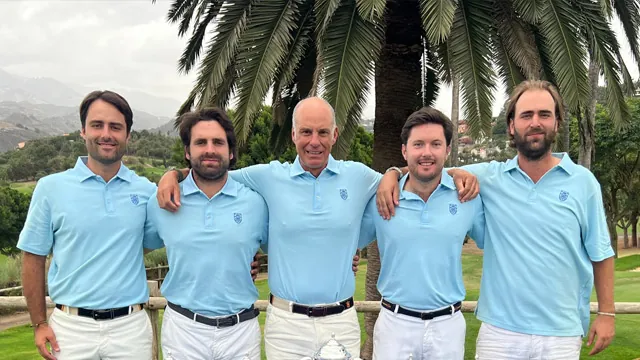 Cinco hombres con polos azul claro y pantalón blanco posan sonrientes junto a una palmera en un campo de golf.