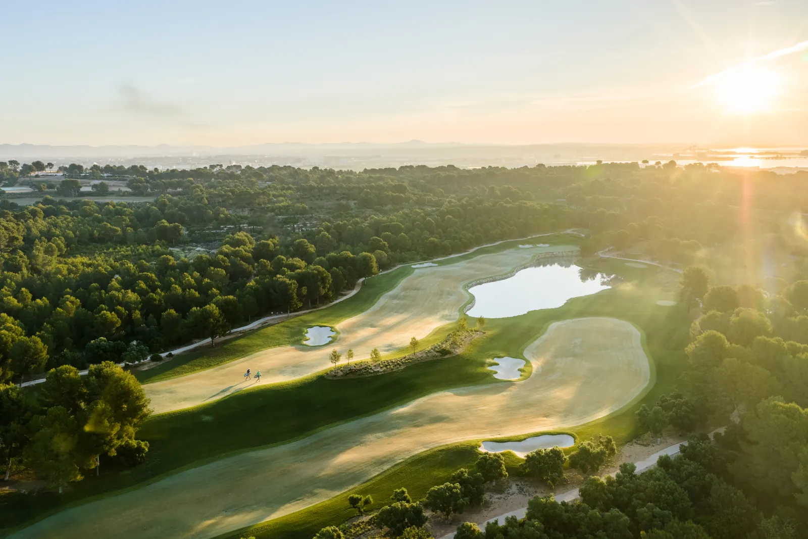 Vista de un recorrido del resort INFINITUM Golf en La Pineda, Vila-seca, con lagos y pinares junto al Mediterráneo